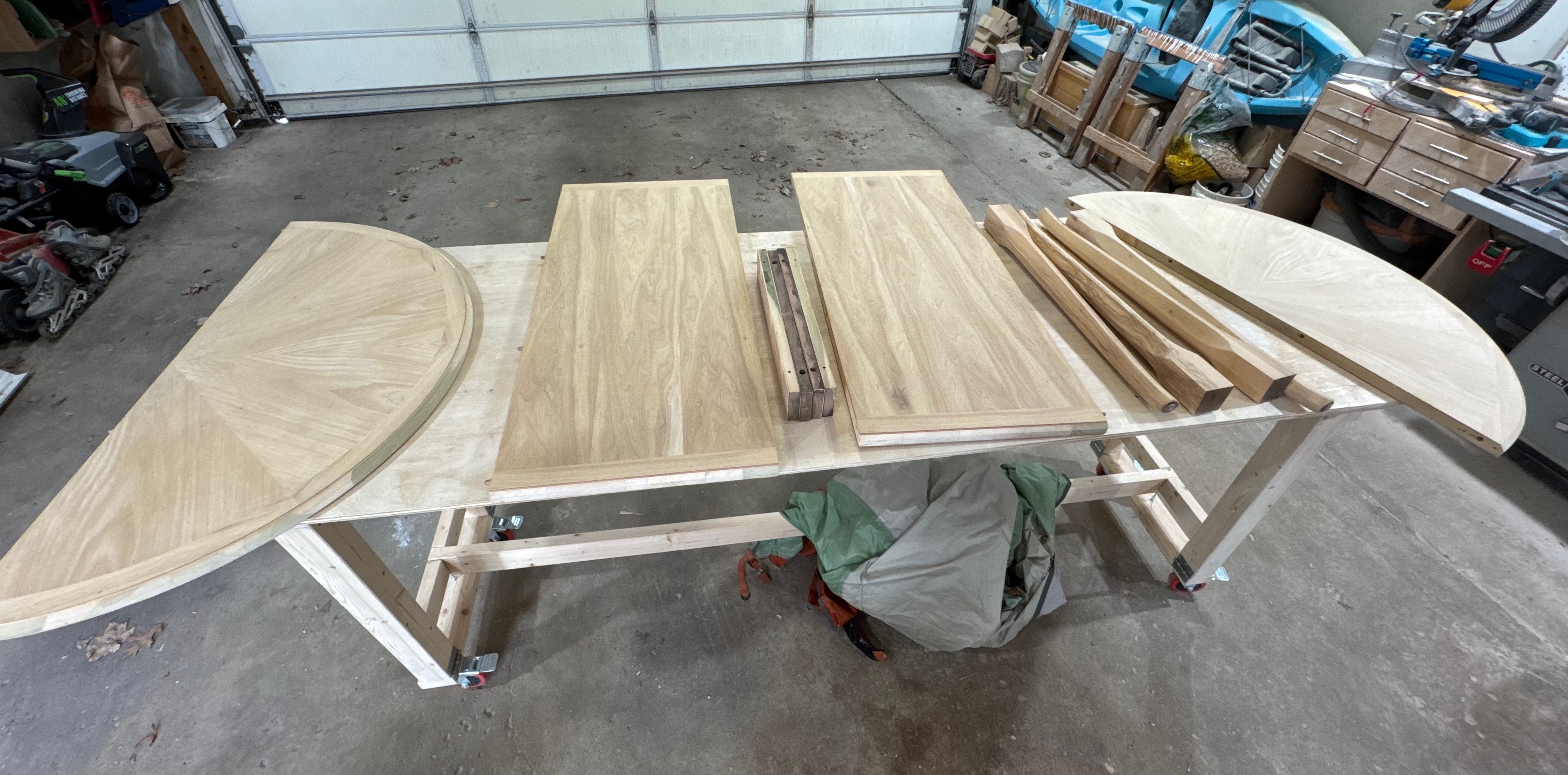 Several wood boards and shapes on a work bench, with various tools in the background.